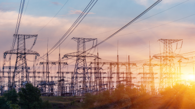 power lines and towers silhouetted by a sunset